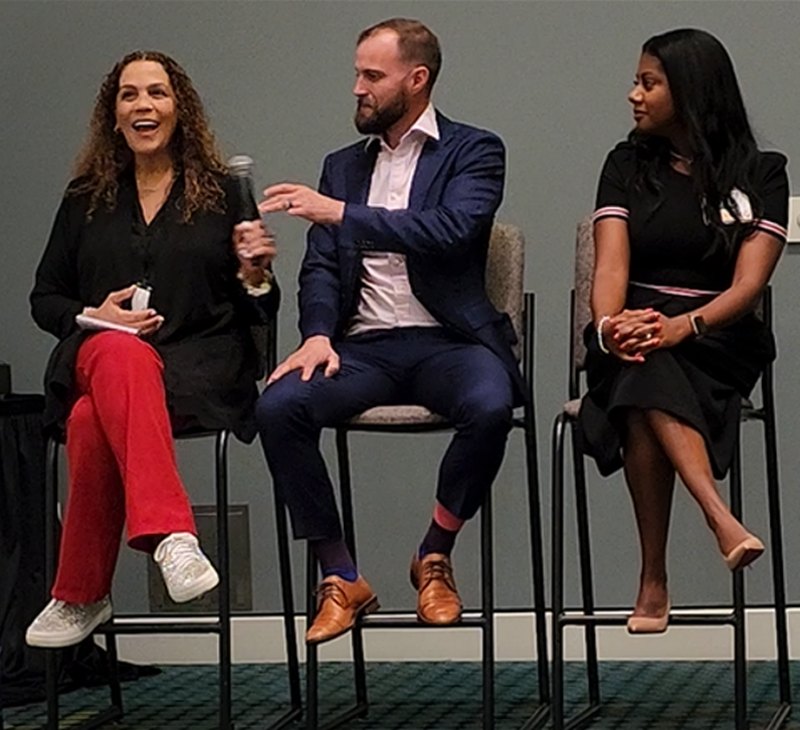 Suha Beidas Zehl, CMB®, AMSP™ with a microphone during an MBA mPact panel discussion